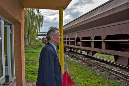 Zrenjanin, Serbia, November 16, 2015. Entry of a freight train into the railway station. The railroad officer is vigilantly watching every freight car that passes by him.のeditorial素材