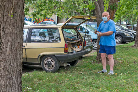Zrenjanin, Serbia, August 14, 2020. A man is servicing his car at the age of Covid 19. He is servicing in the parking lot.のeditorial素材