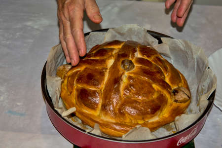 The hands of an elderly housewife who baked a celebration cake - bread for the upcoming celebrations. The bread is baked in the oven from the stove.の写真素材