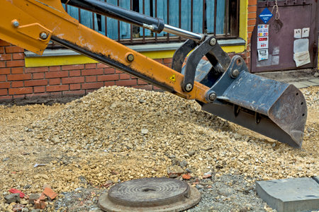 Zrenjanin, Serbia, July 04, 2020. A bucket from an excavator working on the renovation of the sidewalk in the pedestrian zone. The gravel base is stretched by machine.のeditorial素材
