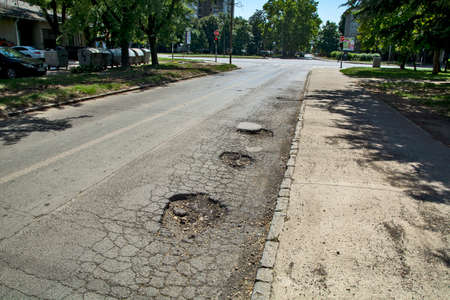 Three big holes on the asphalt road that are very dangerous when it rains. Then it is impossible to spot them from the car.の写真素材