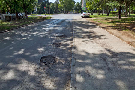 Three big holes on the asphalt road that are very dangerous when it rains. Then it is impossible to spot them from the car.の写真素材