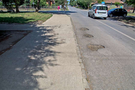 Three big holes on the asphalt road that are very dangerous when it rains. Then it is impossible to spot them from the car.の写真素材