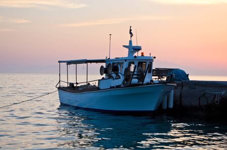 Fishing boat at the dock in sunset, Greece