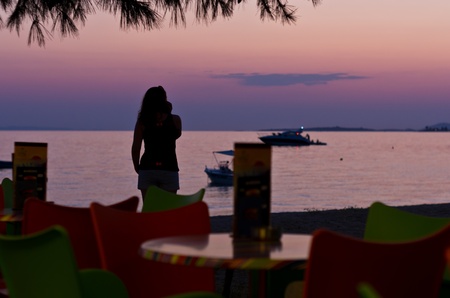 Girl on a beach at sunset, taking a phone call, Sithonia, Greeceの写真素材