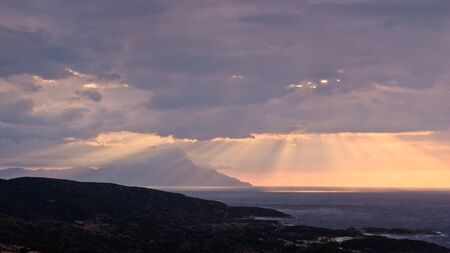 Divine light, stormy sky and sunrise on a landscape around holy mountain Athos in Greeceの写真素材