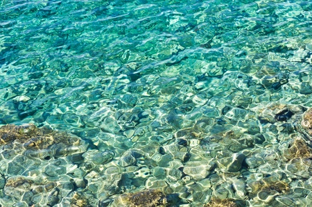 Rocky sea floor visible thru crystal clear turqoise water of Aegean sea in Greeceの写真素材