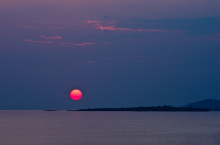 Red sun and sunset at sea below small cape, Sithonia, Greeceの写真素材