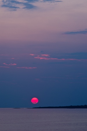Red sun and sunset at sea below small cape at portrait orientation, Sithonia, Greeceの写真素材