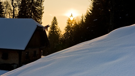 Sunrise reflections on a snow in front of mountaineer house at slovenian alpsの写真素材