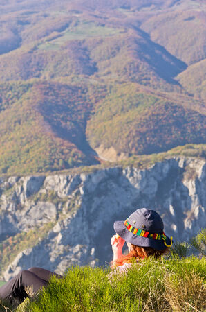 Girl taking a rest and meditate at the top of a 2000 feet vertical cliff over Danube river at Djerdap gorge, east Serbiaの写真素材