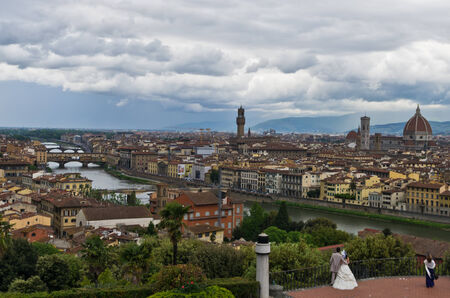 Wedding couple watching panorama of Florence with dramatic sky before a storm, Italyの写真素材