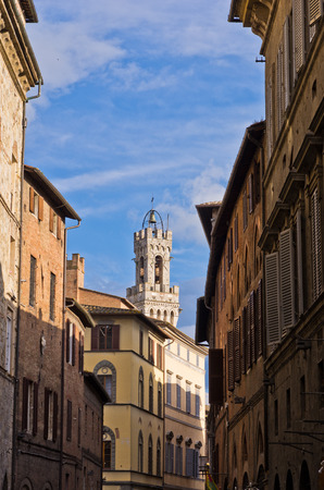 Narrow streets and old buildings in Siena, clock tower on central square is in background, Italyの写真素材