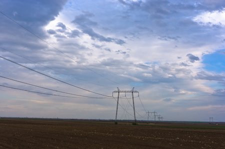 Power lines and heavy clouds on flat agricultural land at early spring, north Serbiaの写真素材