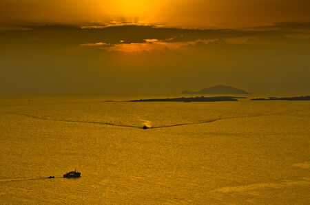 Sunset at sea, with fishing boat and nets between small islands, Sithonia, Greeceの写真素材