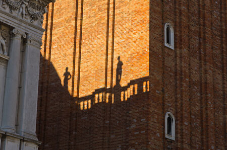 Figurine shadows on a Campanila bell tower wall at piazza San Marco in Venice, Italyの写真素材