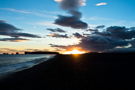 Sunset on black beach near Vik with Dyrholaey rock at background, Icelandの写真素材
