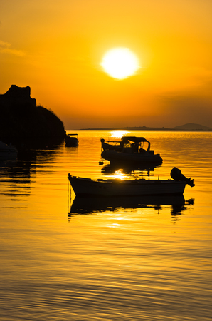 Boat on a calm sea at sunset near old roman fortress in Toroni bay, Sithonia, Greeceの写真素材