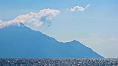 Aegean sea, silhouette of the holy mountains Athos and a small cloud above the mountain top,...