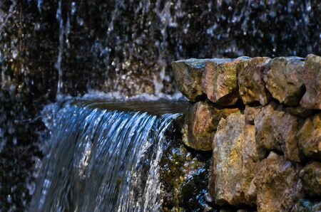 Small water cascade flowing over stone wall in Sardinia, Italyの写真素材