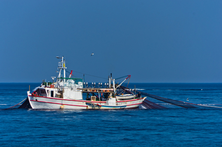 Fishing boat with nests at sea in front of mountain Athos, Greeceの写真素材