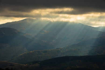 Heavy overcast sky with sunrays over meadows and colorful forests at autumn, mountain Goc, Serbiaの写真素材