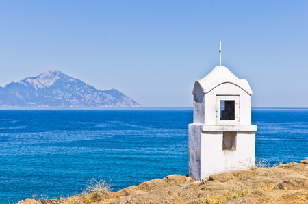 Small white church or chapel with holy mount Athos in background, Greeceの写真素材