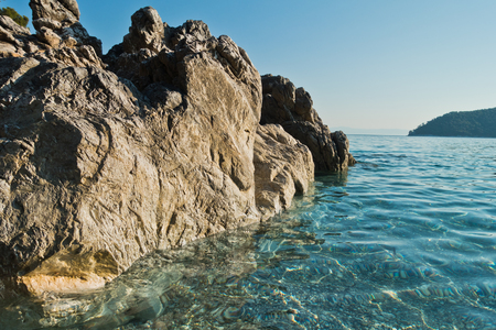 Sea rocks at crystal clear turquoise water at morning, Kastani Mamma Mia beach, island of Skopelos, Greeceの写真素材