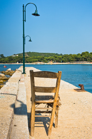 Old wooden chair on a pier in front of Koukounaries beach, morning at Skiathos island, Greeceの写真素材