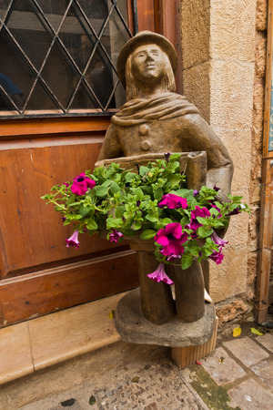 Interesting figurine and flower decoration at doorstep in a narrow winding street of Chania, island of Crete, Greeceの写真素材