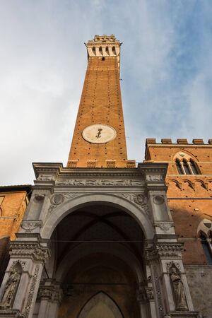 Torre del Mangia, clock tower of a city hall on Piazza del Campo main square in Siena, Tuscany, Italyの写真素材