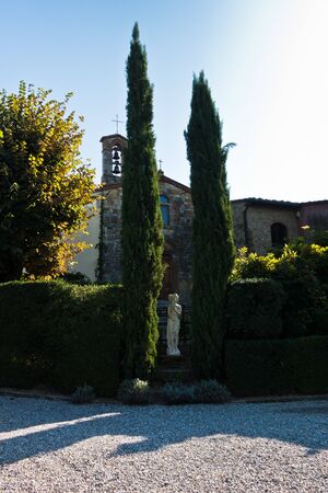Hiking backroads of Tuscany, resting in shadow of cypress trees at villa entrance, near San Gimignano, Italyの写真素材