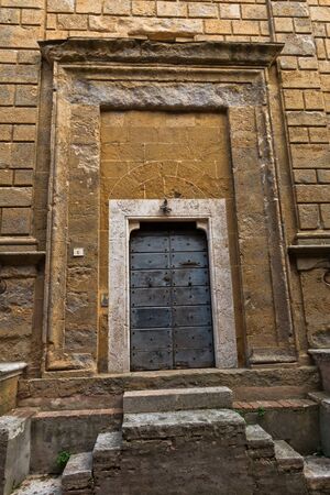 Entrance to an old church at small square in Pienza, Siena province, Tuscany, Italyの写真素材