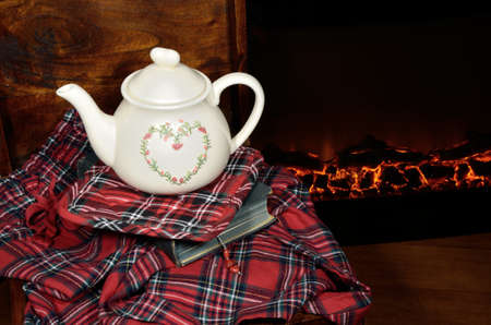 A teapot on a book, by the fireplace, in a cold winter nightの写真素材