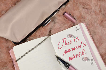 Lady s purse on a pink feather background, with a planner and a notice: This is women's world.の写真素材
