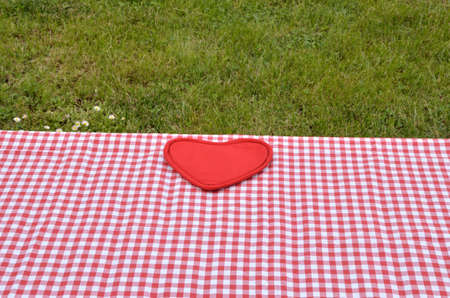 Setting table in the garden - red and white tablecloth with red heart and green grass as a backgroundの写真素材