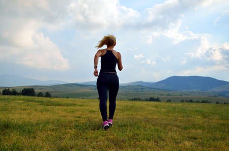 Lady jogging in the mountains field in dusk time