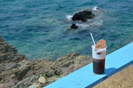 Just made cappuccino with a cookie on blue beach bar table with sea in backgroundの写真素材