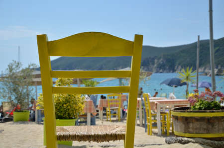 Yellow chair in beach restaurant with sea in backgroundの写真素材