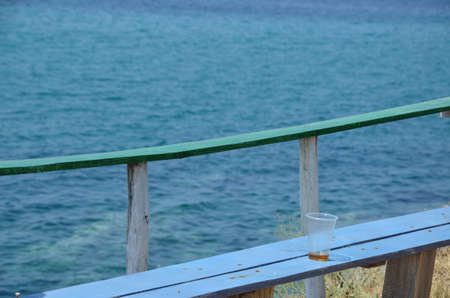 Empty plastic glass left on bar bench and bar table with sea in backgroundの写真素材