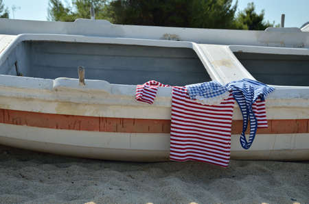 Navy look summer shirts on an old boat set on beachの写真素材