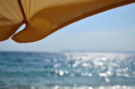 Yellow parasol with sea view - twinkling sea in backgroundの写真素材