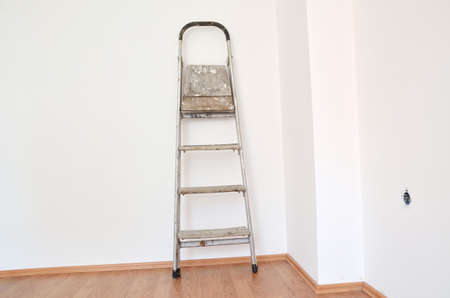 Old used ladder on white clean wall after whitewashing worksの写真素材