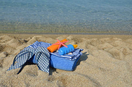 Beach set with flip flops and blue sea coast in backgroundの写真素材