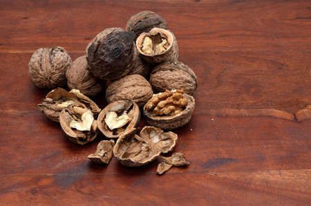 Pile of whole and broken nuts on brown wooden surface