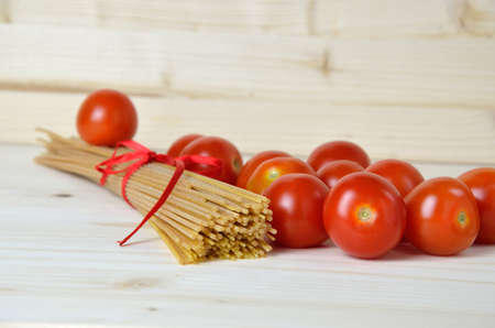 Tomato, and bunch of spaghetti on wooden surfaceの写真素材