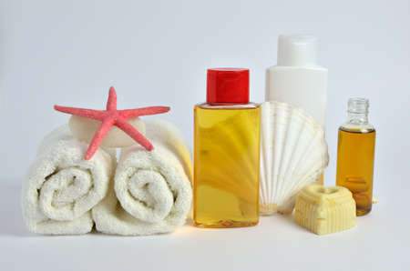 Bottles of lady body cosmetics with white towels and sea symbols as shells, starfish and pebblesの写真素材