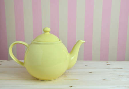 Yellow pot on kitchen table and pink-yellow wall in backgroundの写真素材
