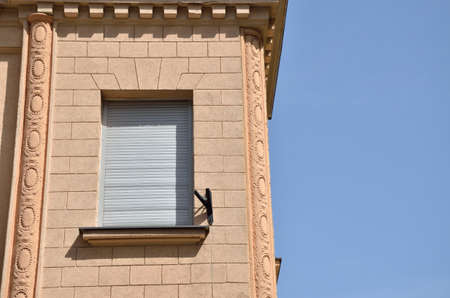 Window covered with sunblind on a renovated building facade and blue sky