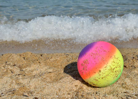 Colorful ball for beach sports with a sea wave behind itの写真素材